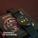Smartwatch KRON WEARZONE preto exibindo controle de atividade na tela, apoiado sobre a caixa