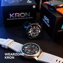Dois smartwatches KRON WEARZONE com pulseiras preta e branca ao lado das caixas do produto